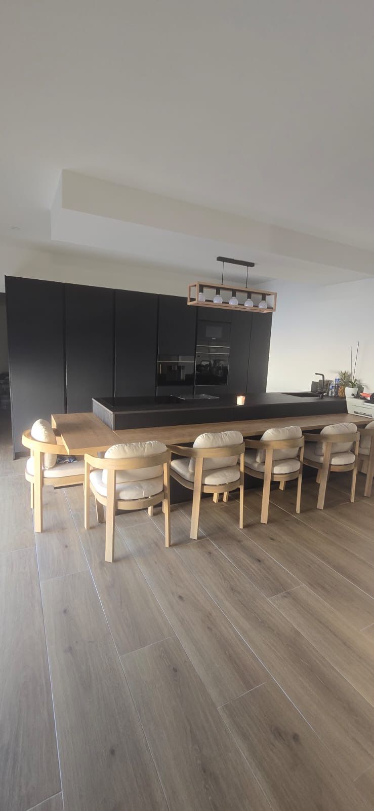 Cuisine noire avec grande table intégrée réalisée par le partenaire